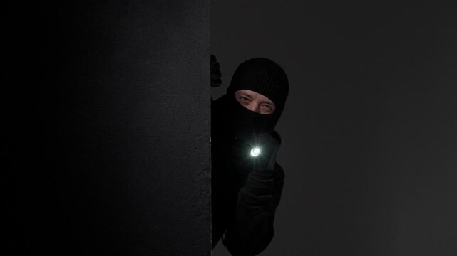 Masked thiefHolding Flashlight in Darkness