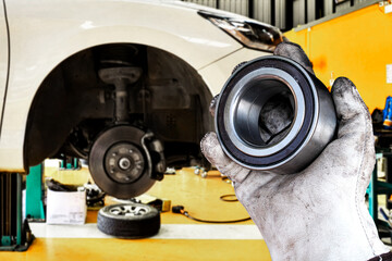Mechanic holding wheel bearing in automotive workshop , Replacing the front wheel bearings of a car , Car maintenance concept