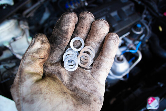 Mechanic hand holding metal flat washers in automotive workshop , metal flat washers for use in automotive repair over engine bay , Car maintenance concept