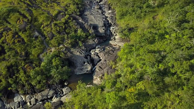 Aerial drone shot tilting up, revealing the dramatic rock formations of Vale da Lua, Chapada dos Veadeiros, bathed in the golden light of sunset in Brazil