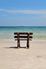 Fototapeta premium Rustic Wooden Bench Facing the Ocean on a Serene Tropical Beach