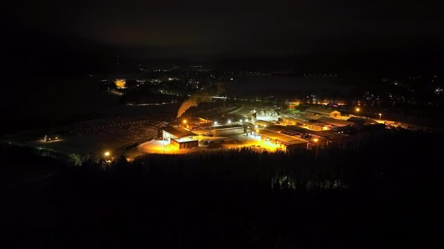 Aerial view around a large wood processing factory, winter night in Finland