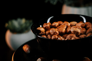 Hazelnuts arranged elegantly in a black bowl against a contrasting dark background