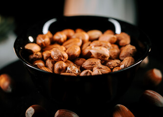 Freshly shelled hazelnuts arranged in a black plate contrasting beautifully against a dark backdrop