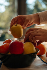 Hand holding apple, bowl of fruit