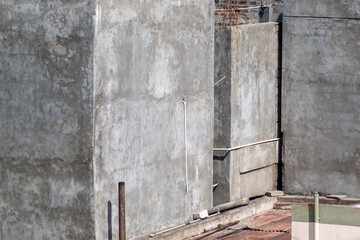 A view of gray concrete walls in an urban area, sunlight illuminating their textures and casting shadows.