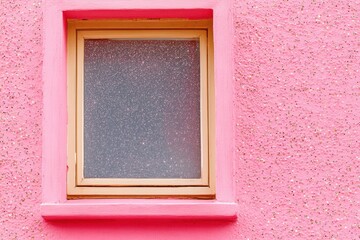 Close up of a small window in a pink wall