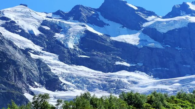 Beautiful summer landscape of the Caucasus Mountains. Alibek glacier and the green valley at Turi Lake, Dombai, Karachay-Cherkessia, Streams of water, snow peak, tract, blocks of ice. North Caucasus