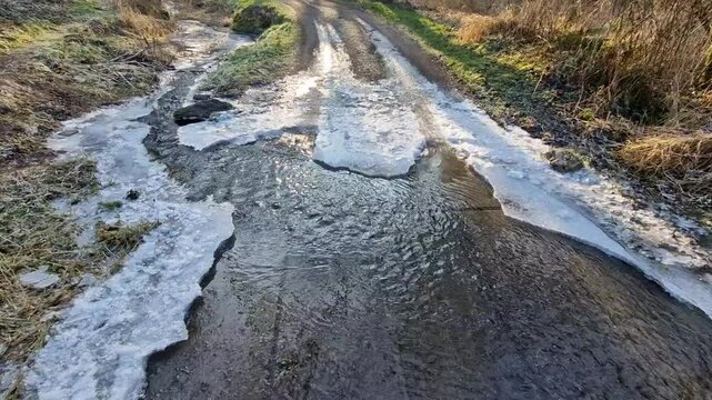 wading through a watercourse on a dirt road in a wooded valley. Ice and snow make the road less passable
