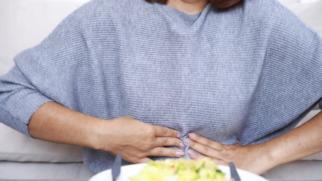 Woman experiencing epigastric burning, pain, and upper abdominal discomfort from dyspepsia and acid reflux after meals, suffering from digestive problems