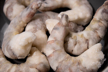 Frozen raw tiger prawns shrimps in a grey bowl on grey kitchen table 