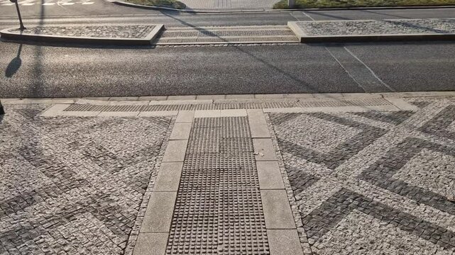 ripples pattern from mosaic cubes on black rough pavement. squares and dashed lines. promenade in the square with repeating lines of the shape of waves and hearts