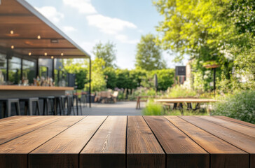 An empty wooden table with a blurred background of a garden and barbecue area on a sunny day