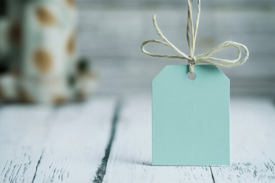 A minimalist blue gift tag with a twine bow on a rustic white wooden table, creating a serene and elegant atmosphere.
