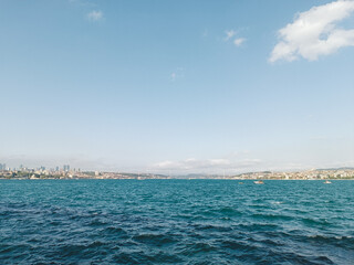 Obraz premium A view of the Bosphorus Strait in Istanbul, with boats scattered across the deep blue water. The city's skyline and buildings are visible in the distance under a clear sky