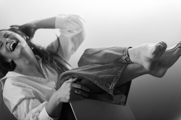 Naklejka premium Beautiful woman in white shirt posing in studio on chair.
