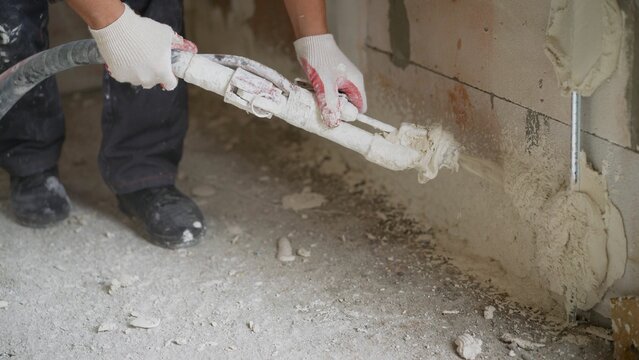 Construction worker applying plaster on ceiling with machine