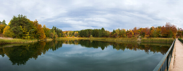 Panoramic view of peaceful and colorful autumn landscape with beautiful reflections in the lake.