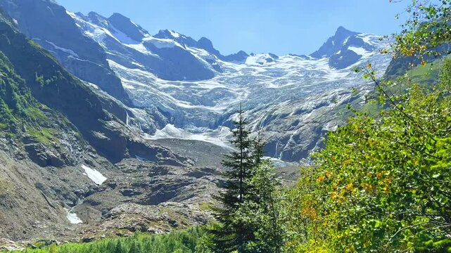 Beautiful summer landscape of the Caucasus Mountains. Alibek glacier and the green valley at Turi Lake, Dombai, Karachay-Cherkessia, Streams of water, snow peak, tract, blocks of ice. North Caucasus