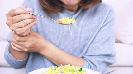Woman’s hand shaking while holding a spoon, experiencing difficulty eating due to Essential Tremor or Parkinson’s Disease