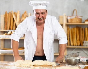 Male baker stands with shirt unbuttoned.