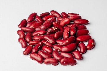 A pile of raw kidney beans on a white background, showcasing their rich color and texture.