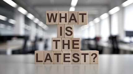 Wooden blocks with words 'What is the latest?'.
