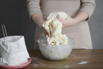 woman makes dough for pasta with her hands in a transparent plate on the table