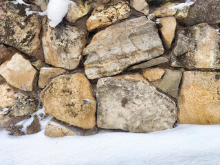 Natural stone wall covered in snow with ample space for text and design elements