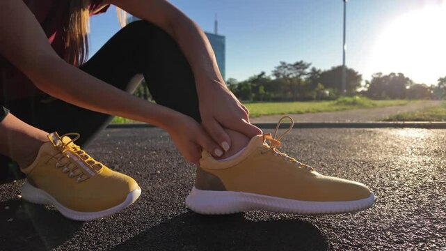 Young woman with ankle and leg pain during jogging and exercise in urban park.