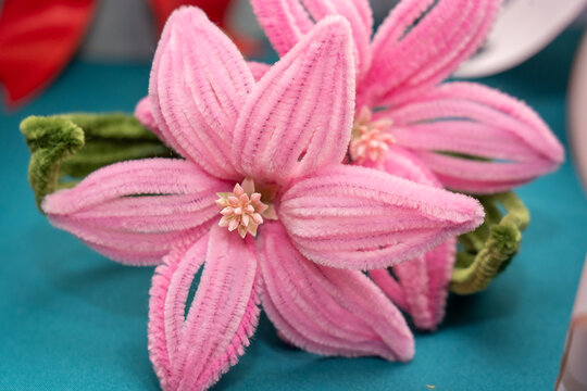 Beautiful pink flowers made of pipe cleaners on a blue background