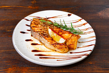 Grilled fish fillet with citrus and balsamic drizzle on plate