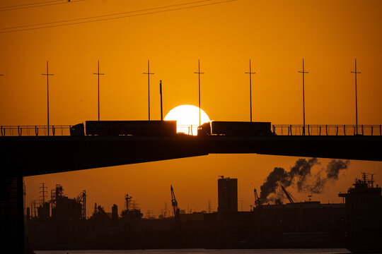 Sunset in the city of Melbourne Over Yarra River with industrial sites and traffic on Bolte Bridge back lit by the setting sun, Docklands, Melbourne, Victoria, Australia