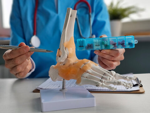 Medical professional examines foot anatomy model while discussing medication schedule concept