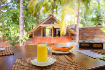 A glass of juice and a tropical style cottage