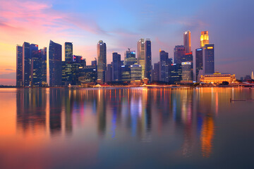 Fototapeta premium A vibrant city skyline at dusk reflected in calm waters.