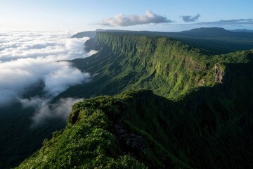 Green mountains meet clouds below, forming an ethereal view for a stock photo