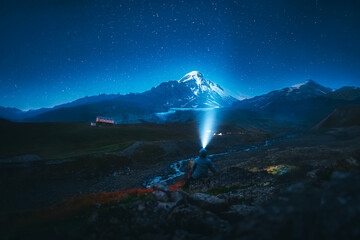 Starry sky above illuminated mountain campsite