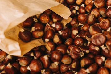 Sweet whole chestnuts in a paper bag for grill. Baked roasted healthy tasty chestnuts, autumn and Christmas vegetarian food. Traditional delicacies in Portugal. Close-up, top view