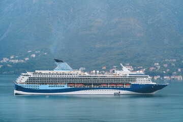 Large white cruise ship sailing on tranquil waters, bathed in the golden light of sunset, against a...