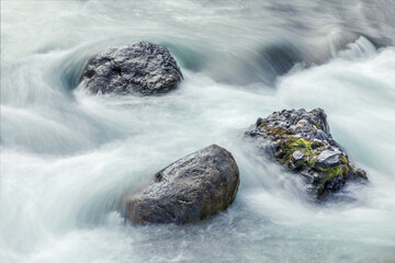 Background with bolders in a river with smooth water, long exposure shot