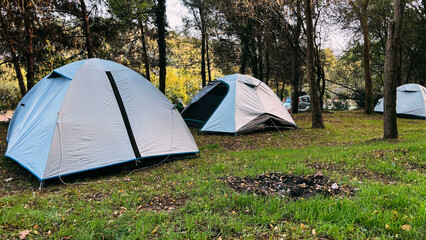 Modern camping tents in the forest on a sunny day. Adventures Camping tourism and tent under view pine forest landscape near clear water and sunset sky in morning at Turkey