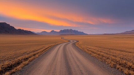 Naklejka premium Desert road winding towards mountains at sunset