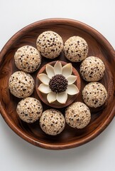 Obraz premium Delicious round treats made from sweetened rice and sprinkled with sesame seeds arranged on a wooden plate with a decorative flower centerpiece