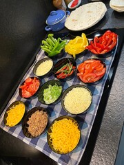 Préparation de tacos : ingrédients colorés et frais sur une table, prêts à être assemblés.