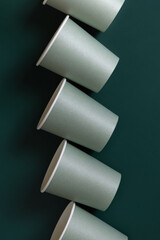 Disposable light green paper cups on a dark green top view, mockup. Sustainable lifestyle