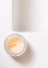 Opened lip balm jar with blank lid on white washbasin top view, cosmetic mockup, lipcare product