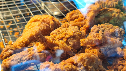Closeup of crispy fried chicken displayed in a glass storefront.