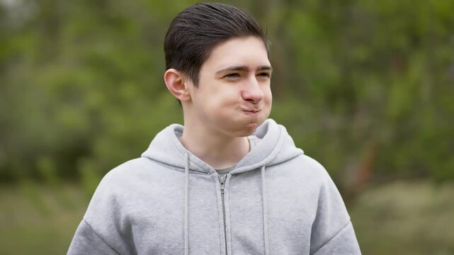 Cheerful playful teenage boy puffing cheeks with air and blowing it out with finger. Joyful adolescent fooling around. Happy young man acting silly, filling cheeks with air and blowing it out