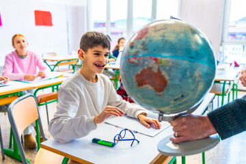 Teacher showing globe to students during geography lesson in classroom © unai